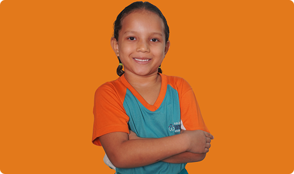 Aluna do Colégio Interação sorrindo, com os braços cruzados, fundo laranja
