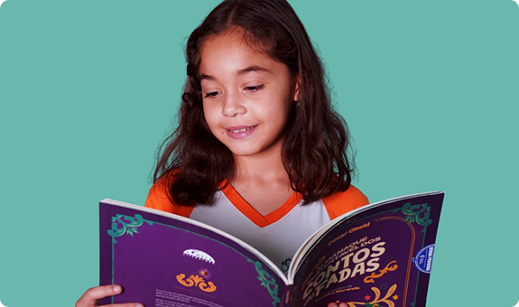 Aluna do Colégio Interação sorrindo enquanto lê um livro
