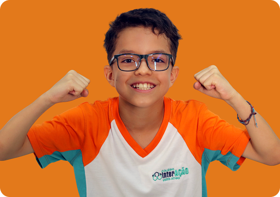 Aluno do Colégio Interação sorridente, flexionando os braços em comemoração
