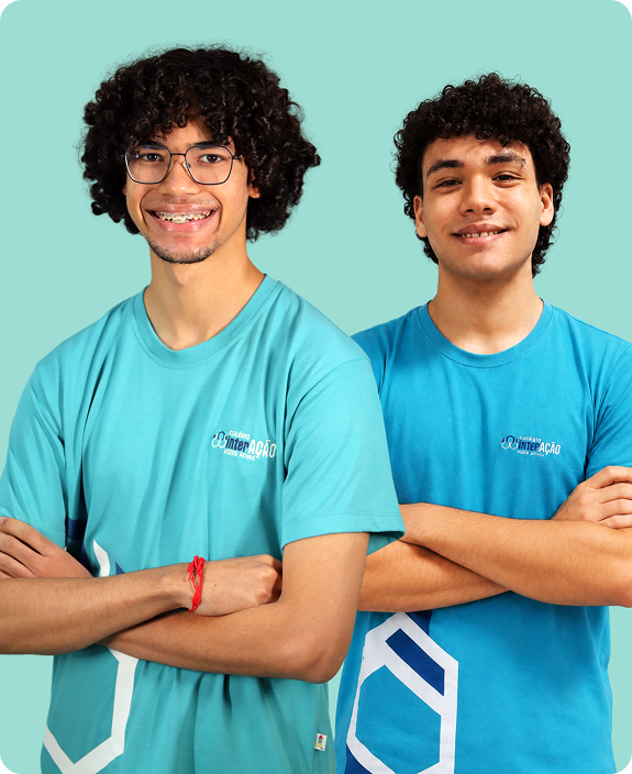 Dois alunos do Colégio Interação sorrindo, de braços cruzados, fundo mint