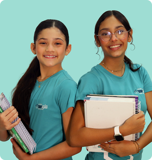 Duas alunas do Colégio Interação sorrindo, uniformizadas, segurando cadernos