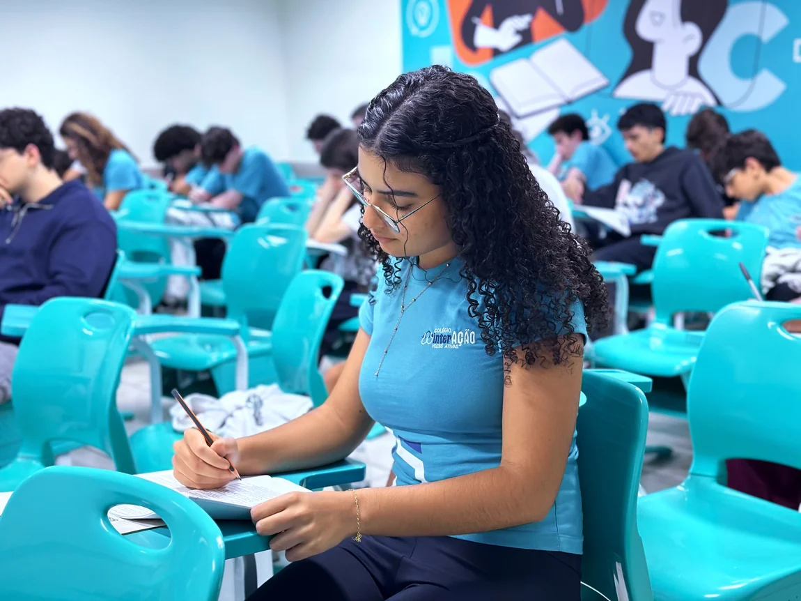 Aluna do Interação escrevendo em sala de aula